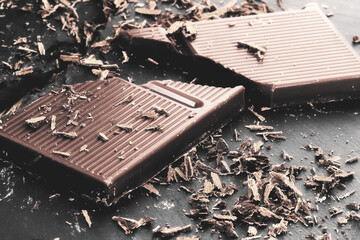 Pieces of dark chocolate on a black wooden background