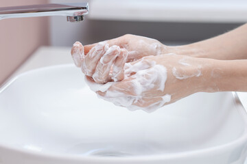 Fototapeta premium Woman washing hands at sink in bathroom, closeup