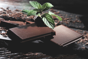 Pieces of dark chocolate on a black wooden background