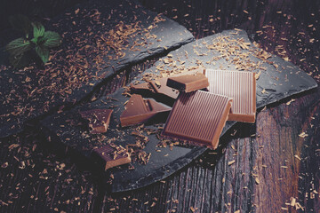 Pieces of dark chocolate on a black wooden background