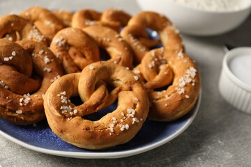 Tasty pretzels with salt on grey table, closeup