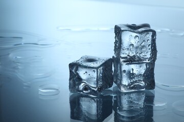 Cubes of clear ice on mirror surface, space for text
