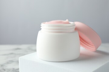 Jar of moisturizing body cream on white marble table, closeup