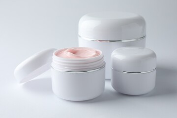 Jars of moisturizing body cream on white background, closeup