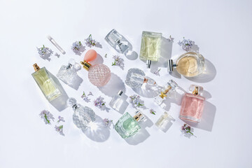 Luxury perfumes and beautiful lilac flowers on white background, flat lay