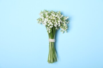 Beautiful lily-of-the-valley flowers on light blue background, top view