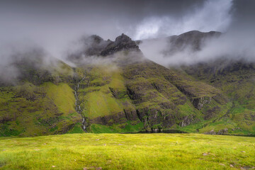 A stunning Carrauntoohil mountain scene, enveloped in thick mist, showcases vibrant greenery and towering rugged peaks in a truly serene setting that captures the imagination, Kerry, Ireland