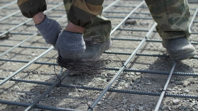 Worker ties reinforcement grid on concrete base