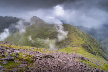 A breathtakingly stunning view of the lush green mountainous terrain enveloped in a soft mist, all under a dynamic, cloudy sky, perfectly capturing natures true essence, Kerry, Ireland