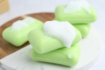 Soap bars with foam on white table, closeup