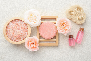 Soap bar, sea salt, essential oils and beautiful roses on beige table, flat lay