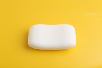 Soap bar on yellow background, above view