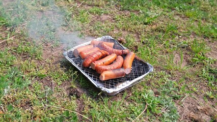 Tasty Fat Dripping Sausages Grilled on Disposable Single Use Portable Charcoal Grill