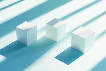 Three white cubes on a light teal surface, bathed in sunlight casting long shadows