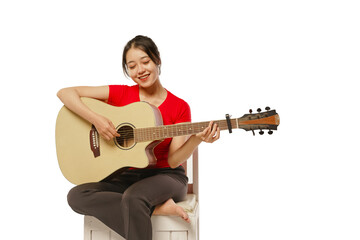 Beautiful Asian woman wearing headphones playing guitar and singing in recording studio