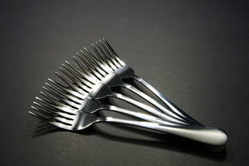 Close up shot of silver fork layered together side by side with dark background, Food conceptual...