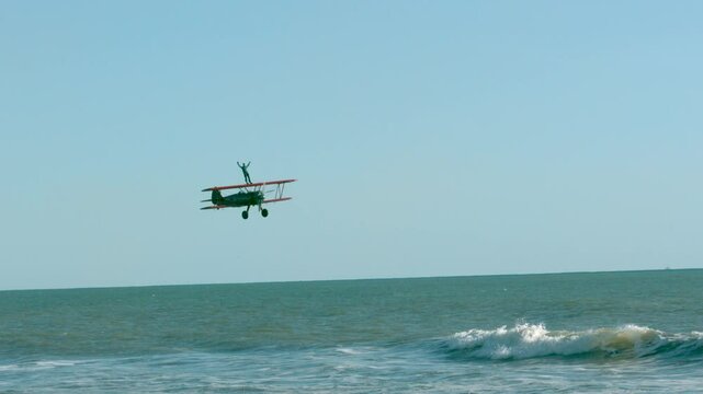 Epic stunt of man standing on airplane as it soars over ocean waves - slow motion at 1000 FPS