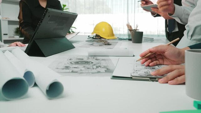 A diverse team engages in a collaborative engineering meeting, utilizing blueprints and technology in a modern workspace to inspire creativity and design solutions. SACTR