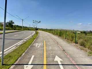 Estrada com vias para pedestre e ciclista com fundo para natureza e ceu azul.