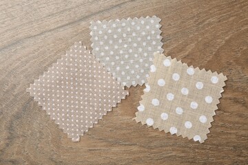 Samples of different fabrics on wooden table, flat lay