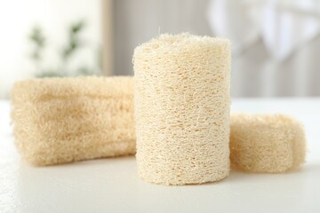 Different loofah sponges on white table, closeup