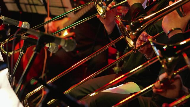 A vibrant jazz scene featuring musicians playing trombones. Microphones capture the lively atmosphere. Close-up of the trombone section