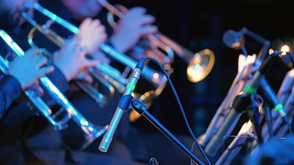 The big band's trumpet section. A vivid scene of musicians playing trumpets in a dimly lit hall. Focus on the microphone, musicians blurred - Powered by Adobe