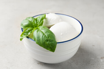 Tasty mozzarella cheese and basil on light table, closeup