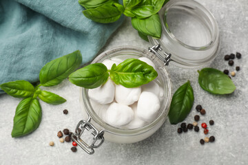 Mozzarella cheese balls with basil and peppercorns on light grey table, flat lay