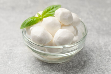 Mozzarella cheese balls and basil on light grey table, closeup