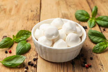 Mozzarella cheese balls with basil and peppercorns on wooden table, closeup