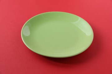 One empty plate on red background, closeup