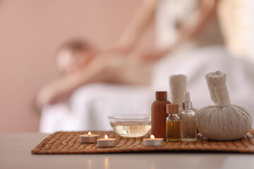 Woman receiving back massage in spa salon, focus on essential oils and burning candles