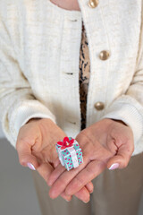 Woman hands holding gift box with red bow, close-up. Vertical photo. High quality photo