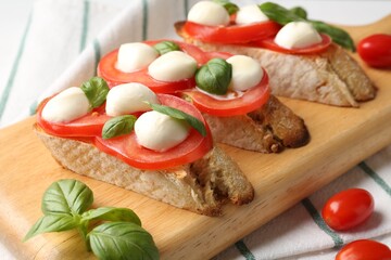 Tasty sandwiches with mozzarella cheese, tomatoes and basil on table, closeup
