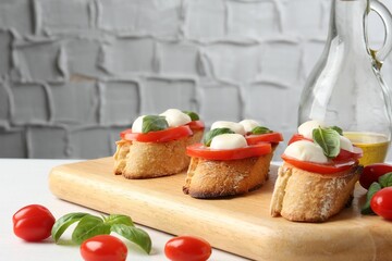Tasty sandwiches with mozzarella cheese, tomatoes and basil on white table, closeup. Space for text