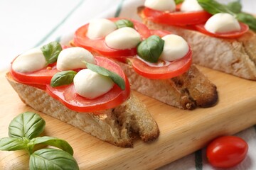 Tasty sandwiches with mozzarella cheese, tomatoes and basil on table, closeup