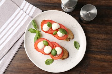Tasty sandwiches with mozzarella cheese, tomatoes and basil on wooden table, flat lay