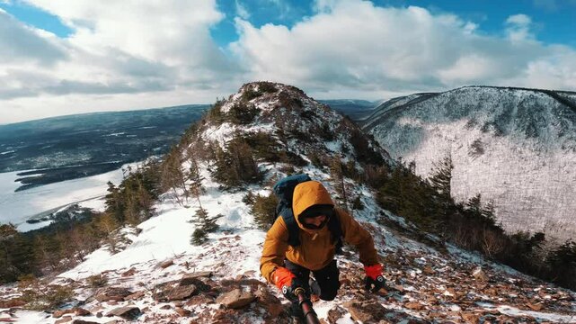 man ascending snowy mountain along the Cabot Trail in Nova Scotia, Canada. The ocean behind him