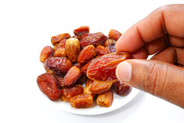Picking a date fruit with bunch of dates with plate close-up view 