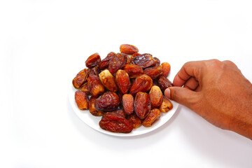Picking a date fruit with bunch of dates with plate close-up view 