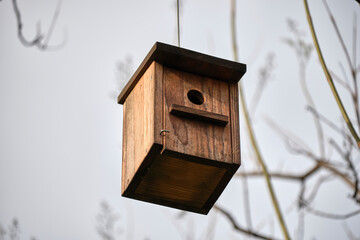 Rustic wooden birdhouse hanging outdoors on a cloudy day