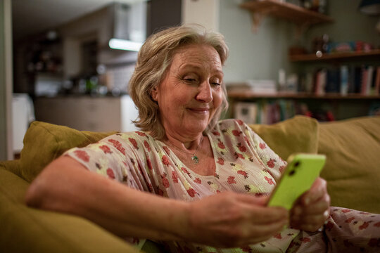 Senior woman relaxing at home scrolling on her smartphone