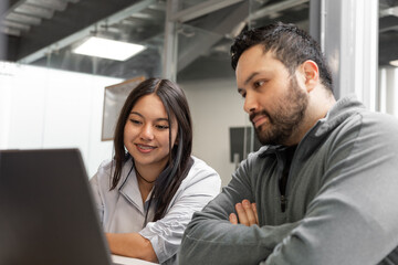 Coworkers focus on the laptop screen, reviewing information with attention in a collaborative and professional setting.



