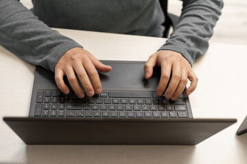 A detailed view of hands actively typing on a laptop keyboard. The image highlights concentration...