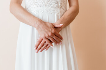 Bride's Hands Clasped in Anticipation, Wedding Dress Detail, Soft Peach Background, Elegant...