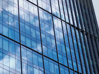 Modern glass office building facade with geometric pattern of blue reflective windows and metal framework