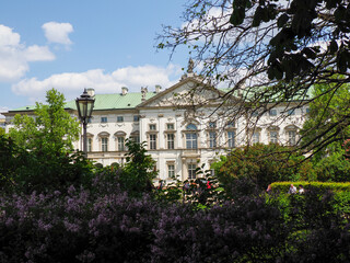 Historic neoclassical palace building with ornate architecture surrounded by blooming spring gardens