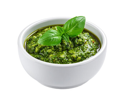 A white ceramic bowl filled with vibrant green pesto sauce, textured with basil, on transparent background