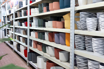 Colorful flower pots arranged neatly on shelves in a garden center, presenting a diverse selection...